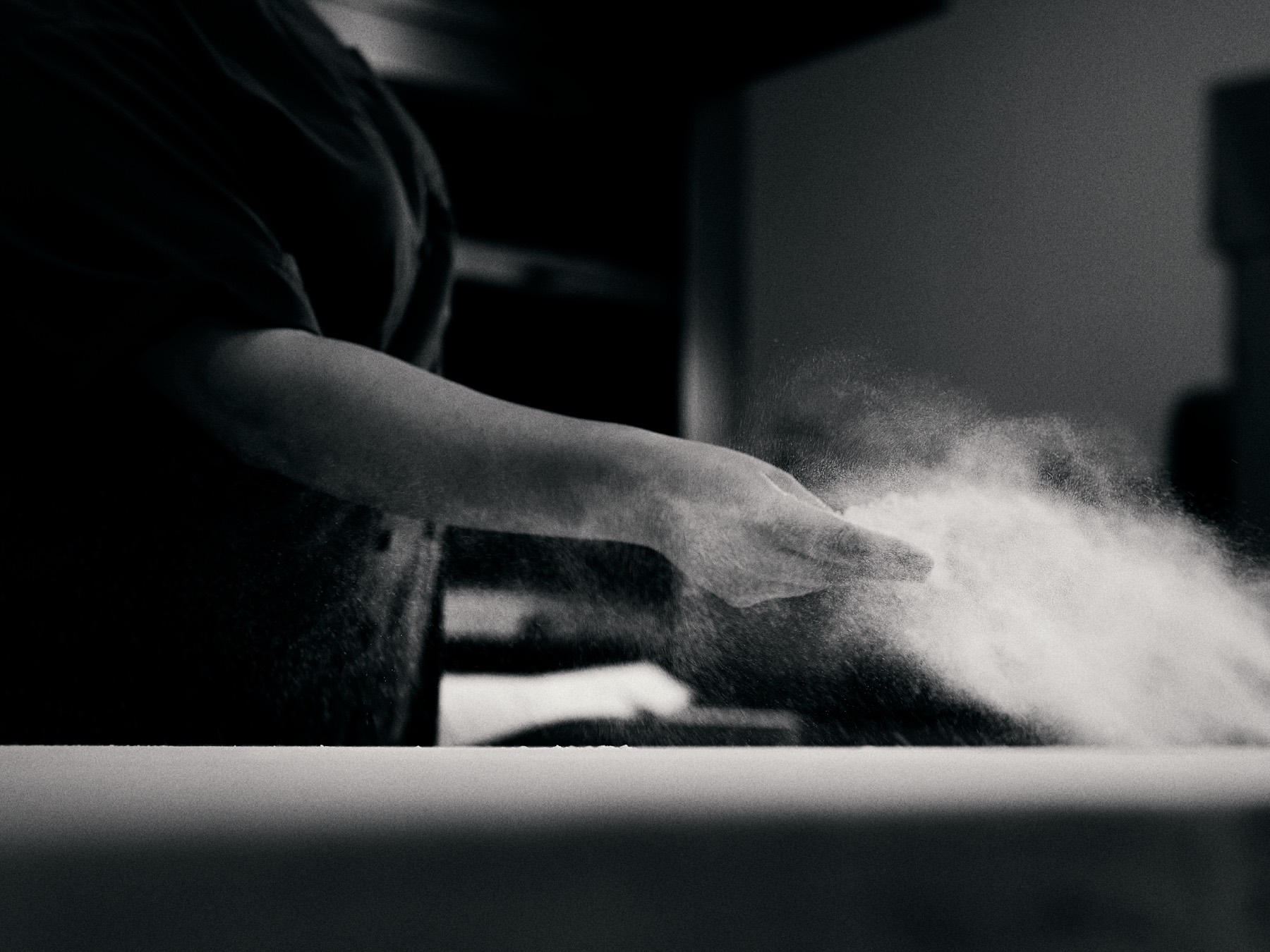 Baker dusting flour over proofing baskets